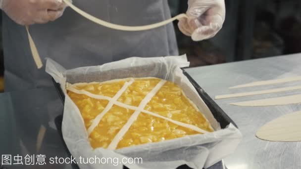 人准备水果橙色柠檬馅饼在厨房桌上, 最后的装饰在手套, 餐厅厨房烘焙产品工厂